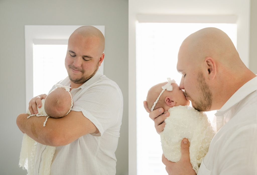 Indianapolis newborn photography session images of dad holding newborn baby girl in front of window