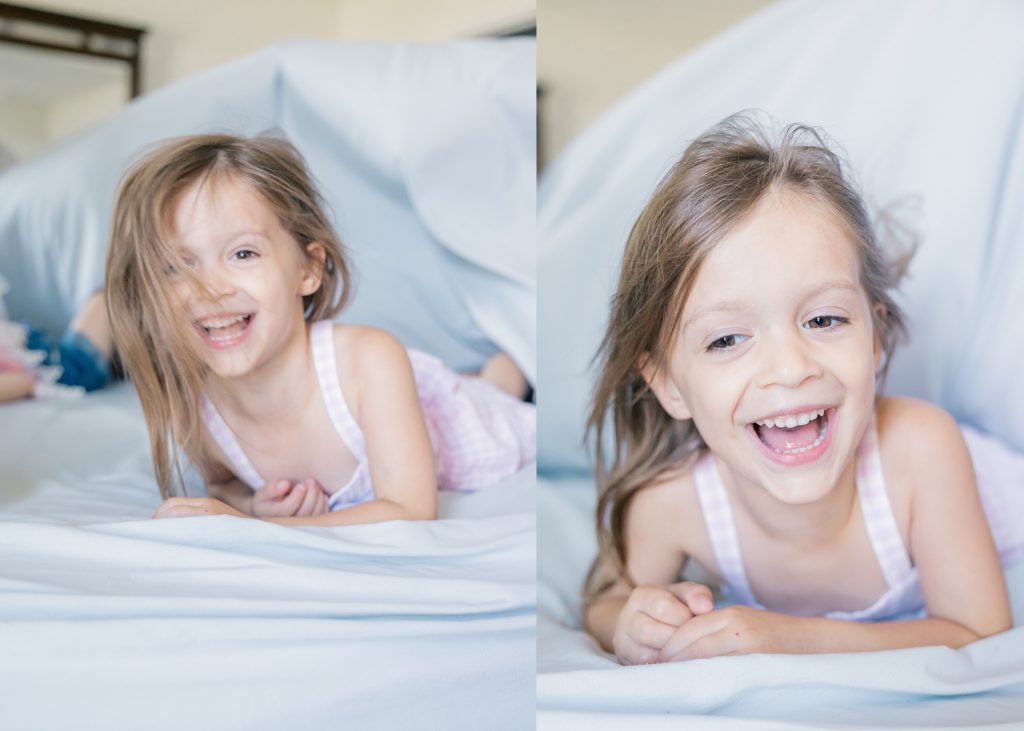 Indianapolis in home family session little girl in pink dress playing peek a boo with blue sheet on bed
