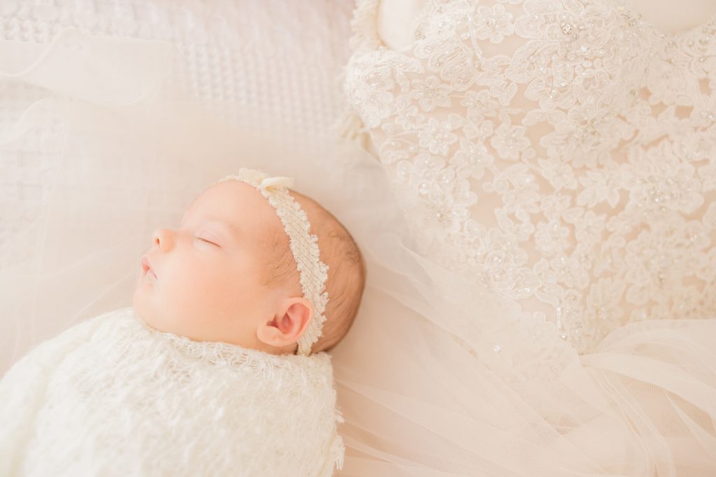 Indianapolis newborn photographer, baby lying on mother's wedding dress while swaddled in cream