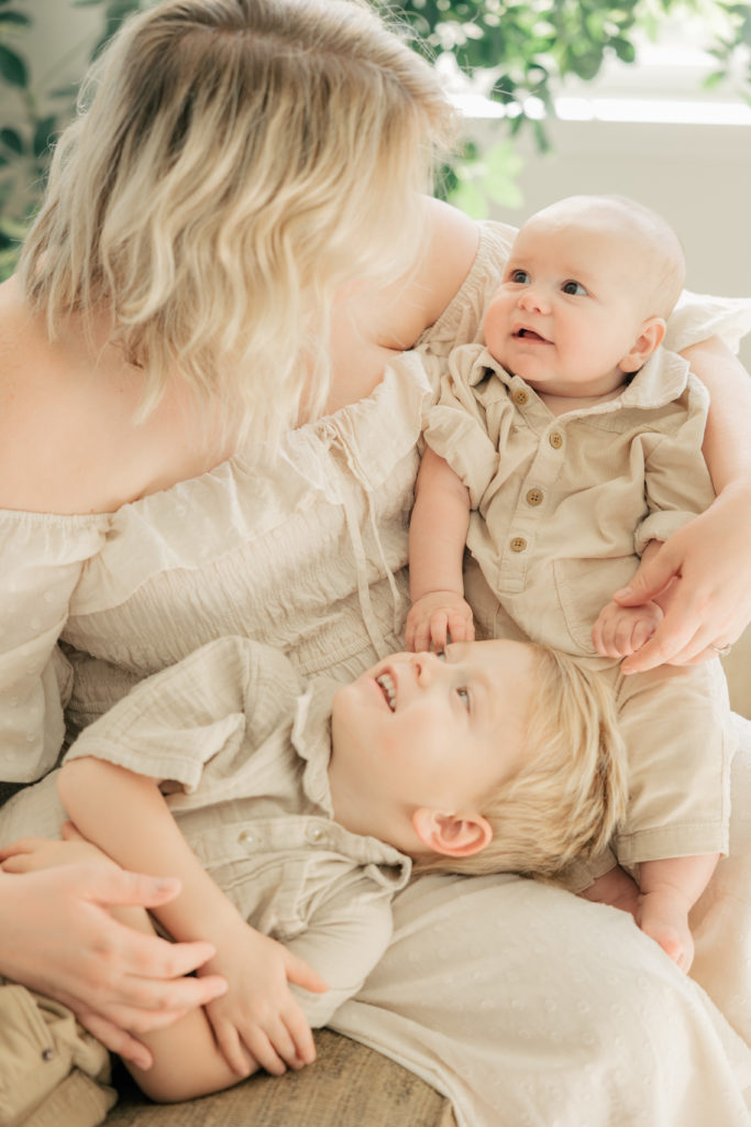 mother and sons snuggling on the couch wearing creams during their session with Indianapolis professional photographer brittney lear photography