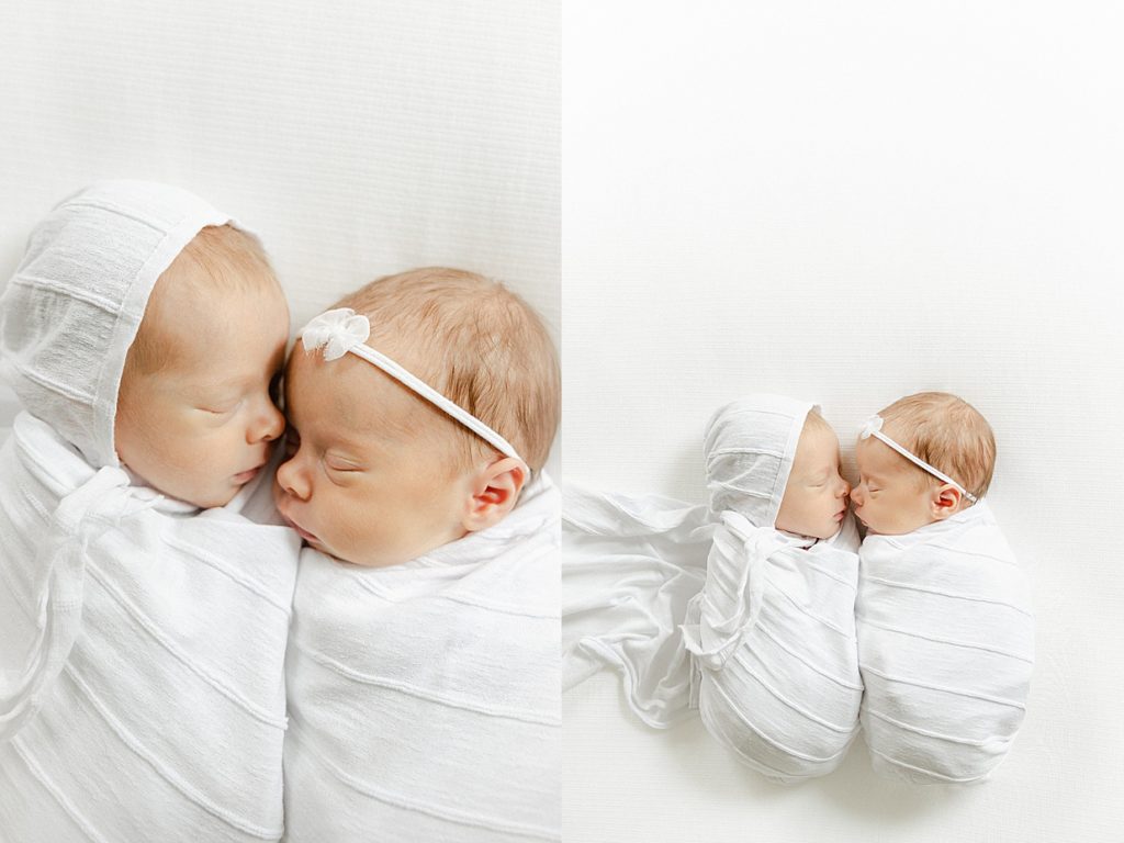 Newborn twins swaddled in white laying on a white blanket facing each other