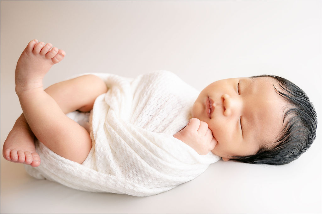 Newborn baby sleeps with legs crossed in a studio indianapolis birth center