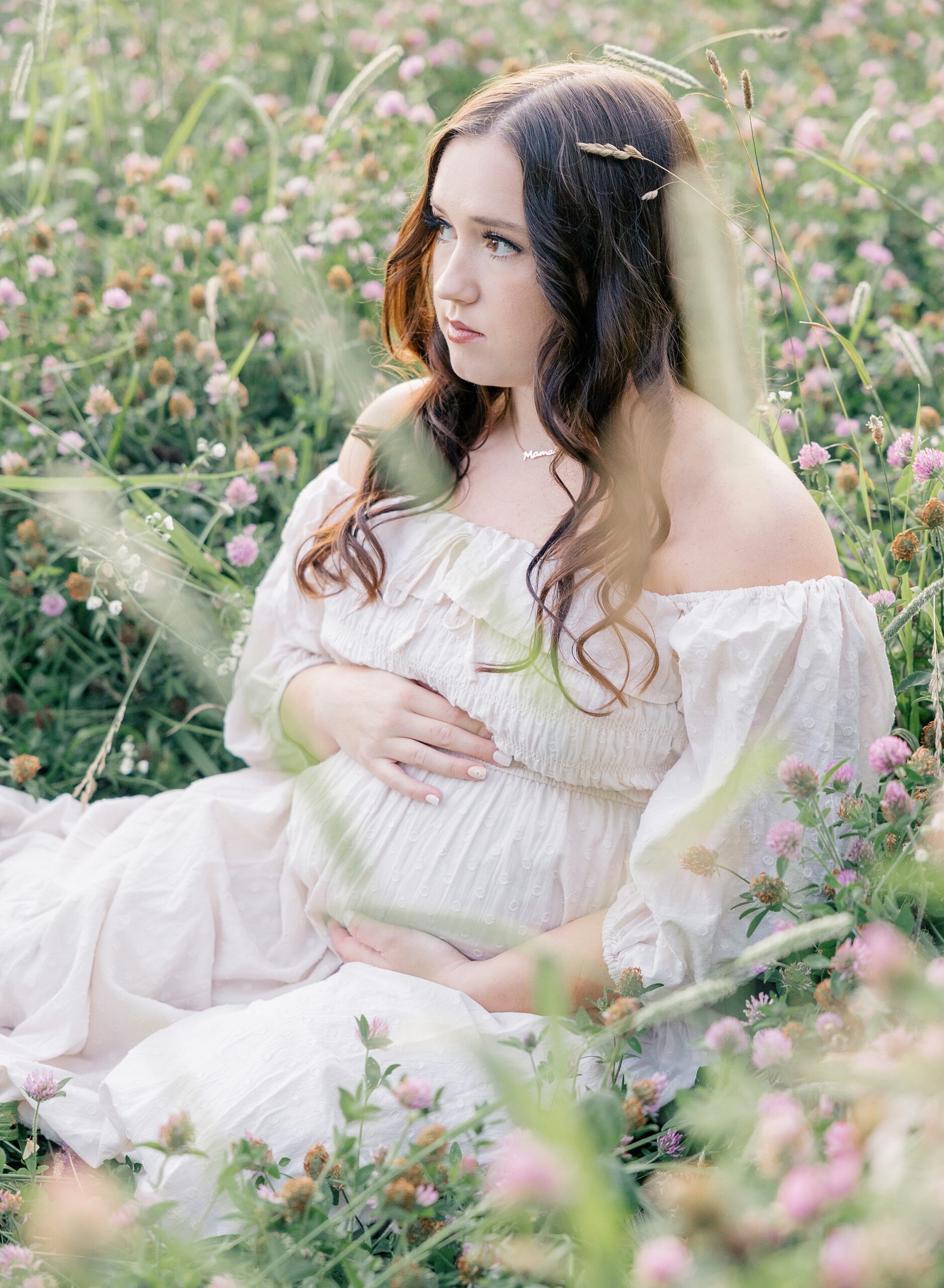 Mother sitting in field of flowers in cream dress holding baby bump, session styling tips, Zionsville maternity photographer