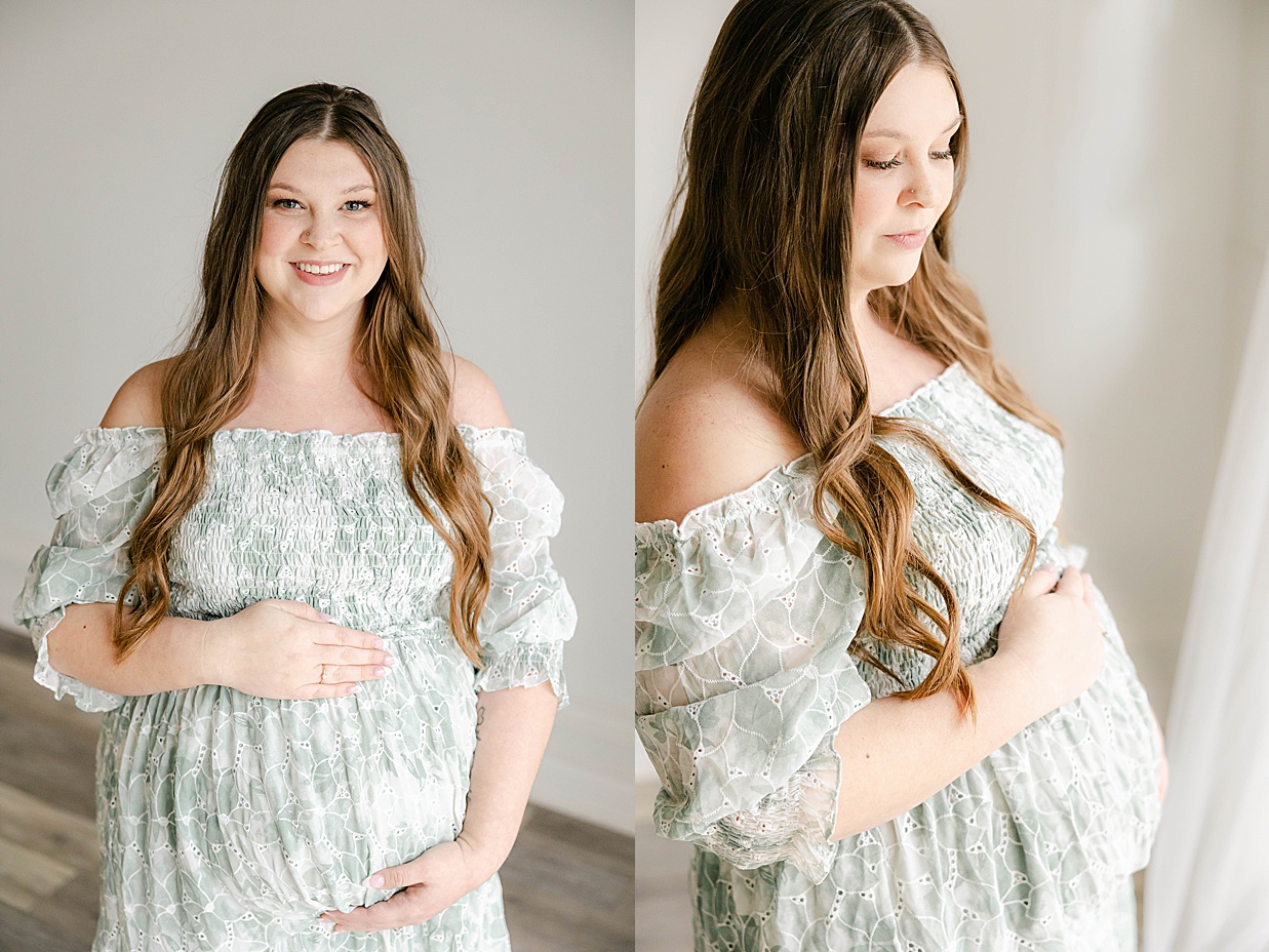 Pregnant mother in a sage green dress holds her baby bump while smiling, Maternity photography in Zionsville