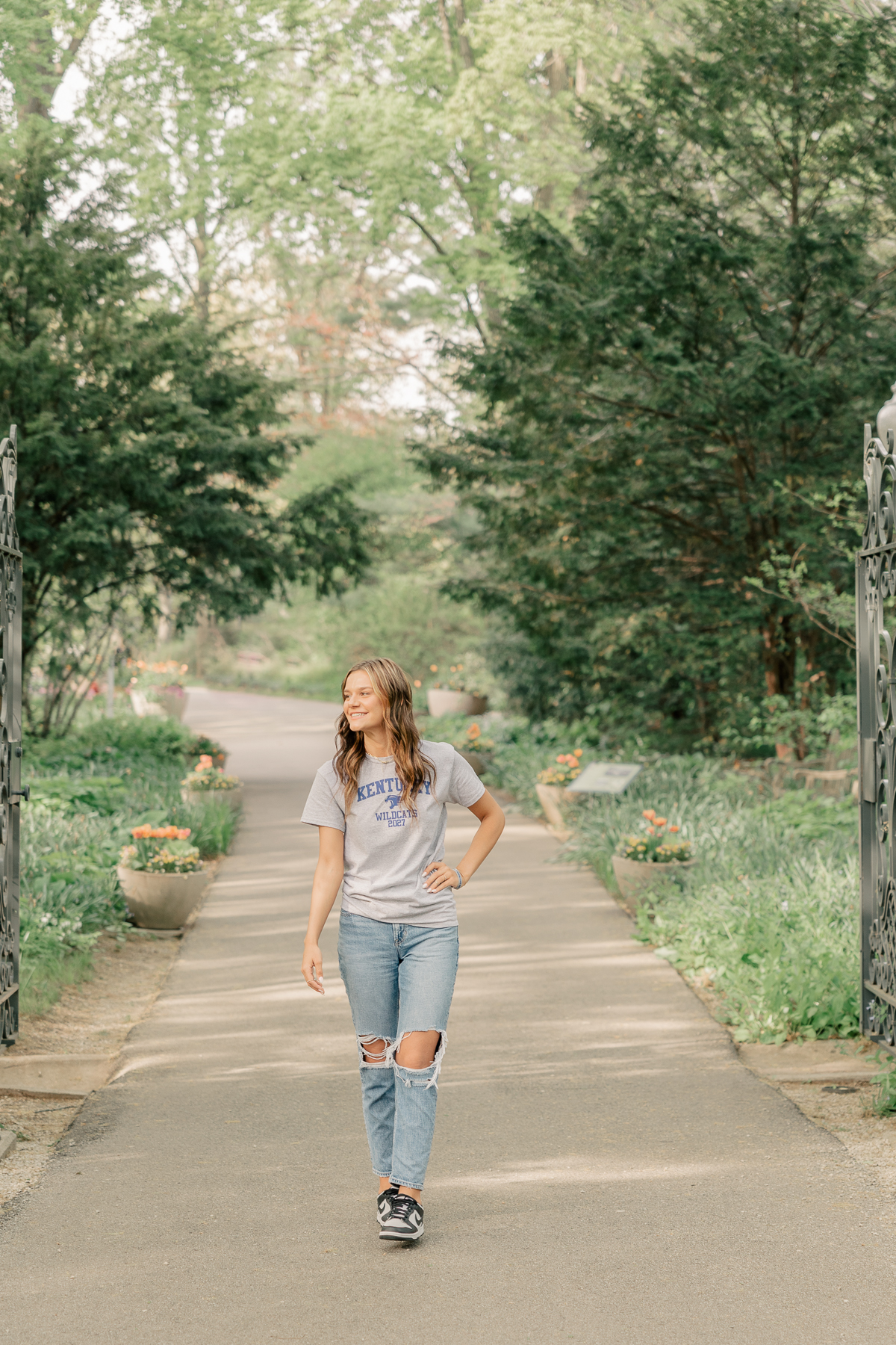 girl in a kentucky university shirt and jeans walks at Newfields, Indianapolis Senior Pictures