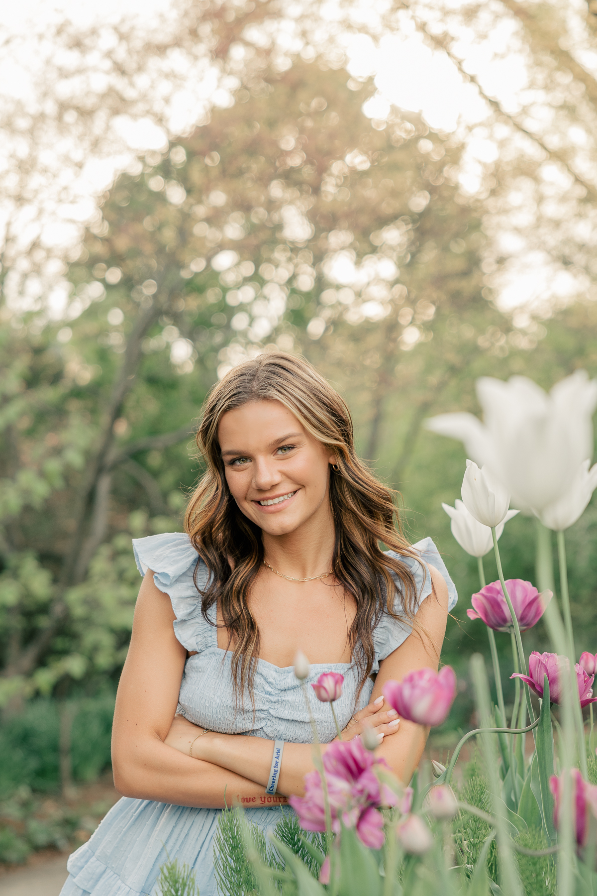 girl in a short blue dress  stands surrounded by flowers at Newfields, Indianapolis Senior Photographer