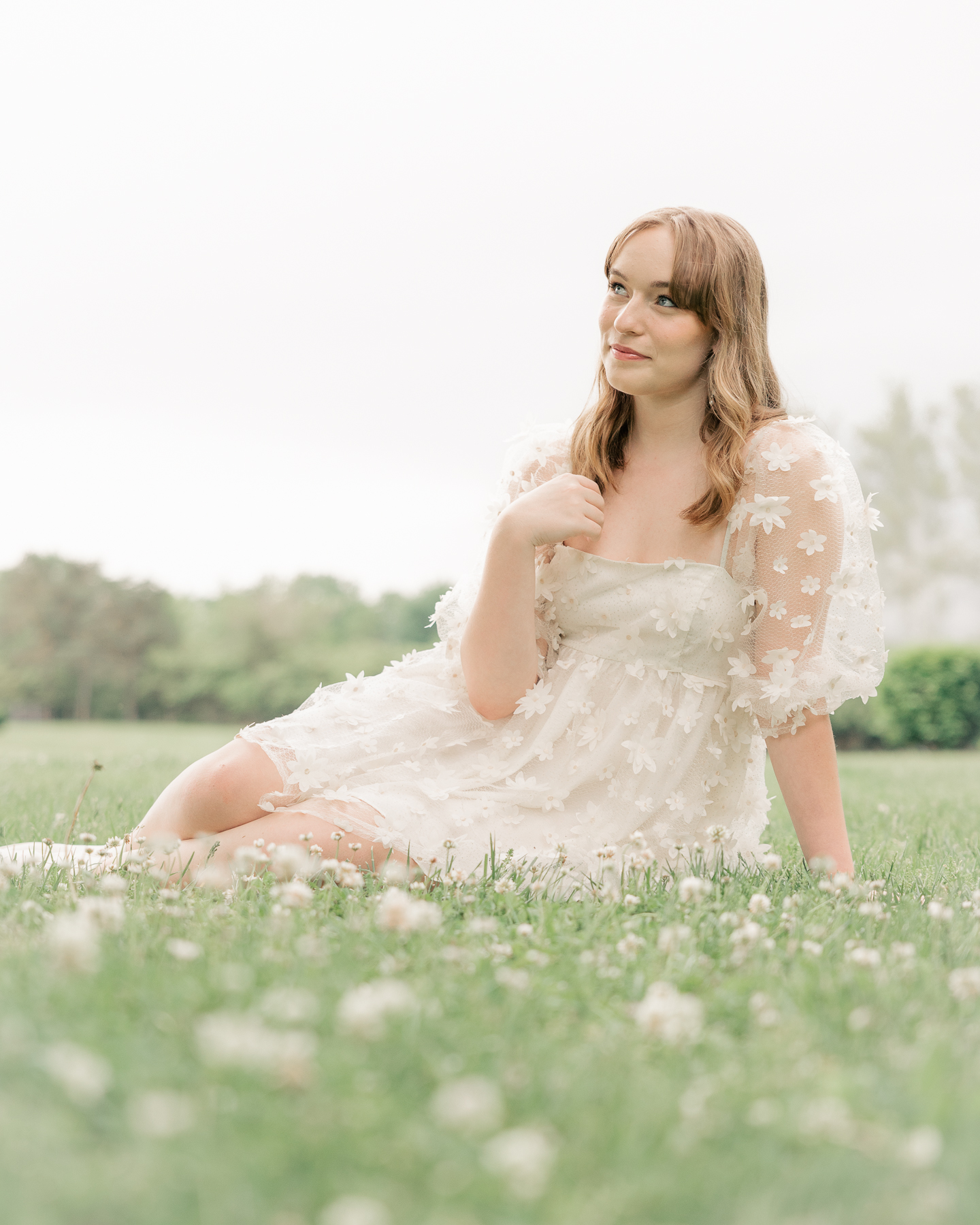girl in short white floral dress sits in field, Plainfield senior photography