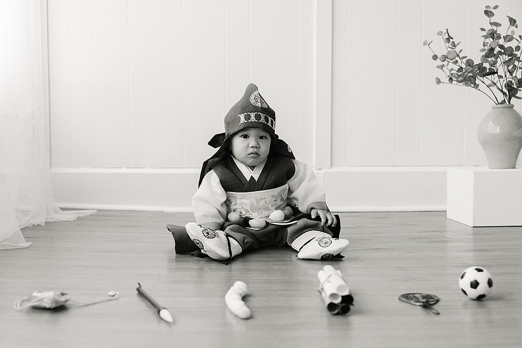 A young toddler in a traditional Japanese outfit sits on a floor with toys around him moonshot toys