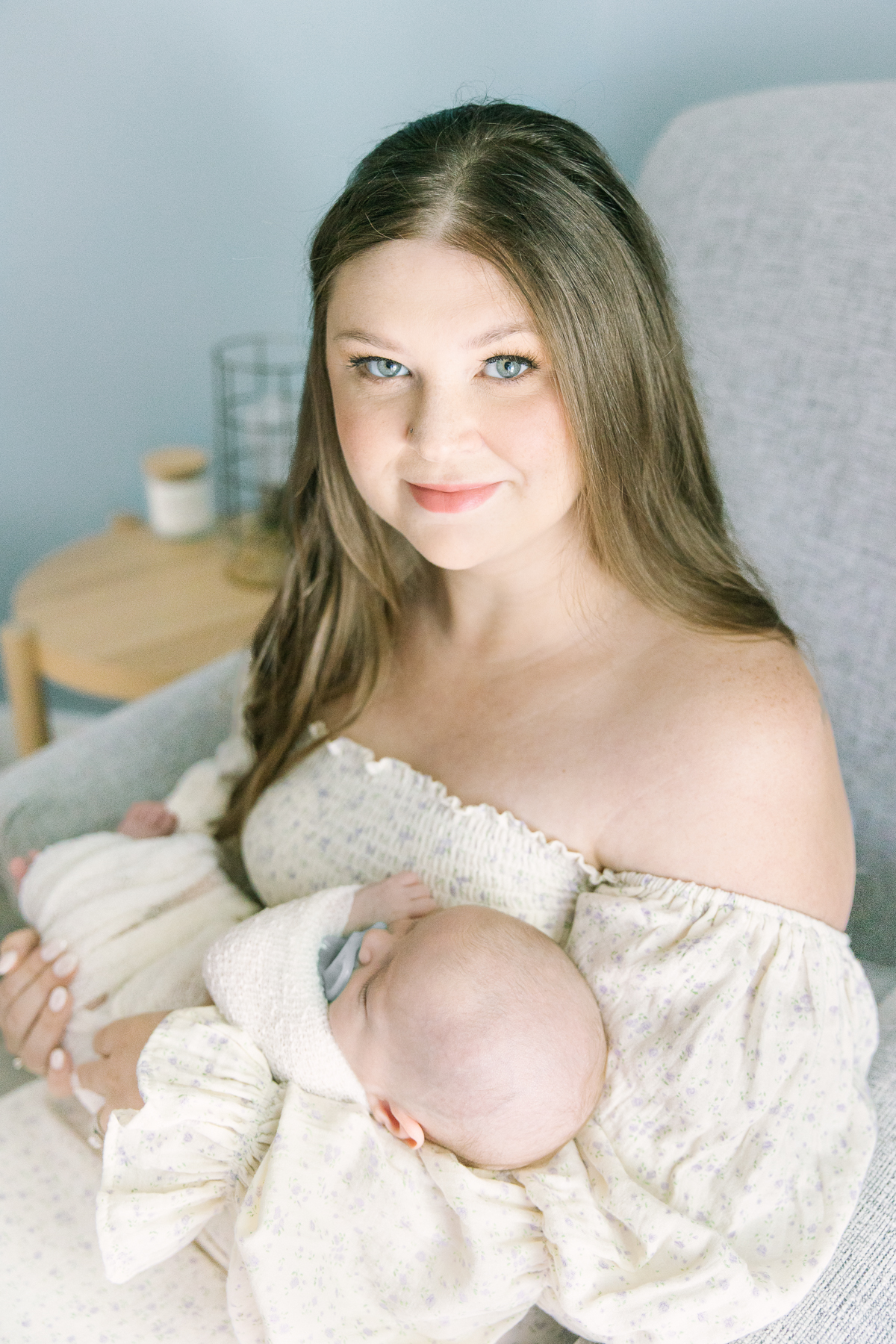 Mother looks at camera while holding newborn baby boy in her arms in her home, lifestyle newborn photography