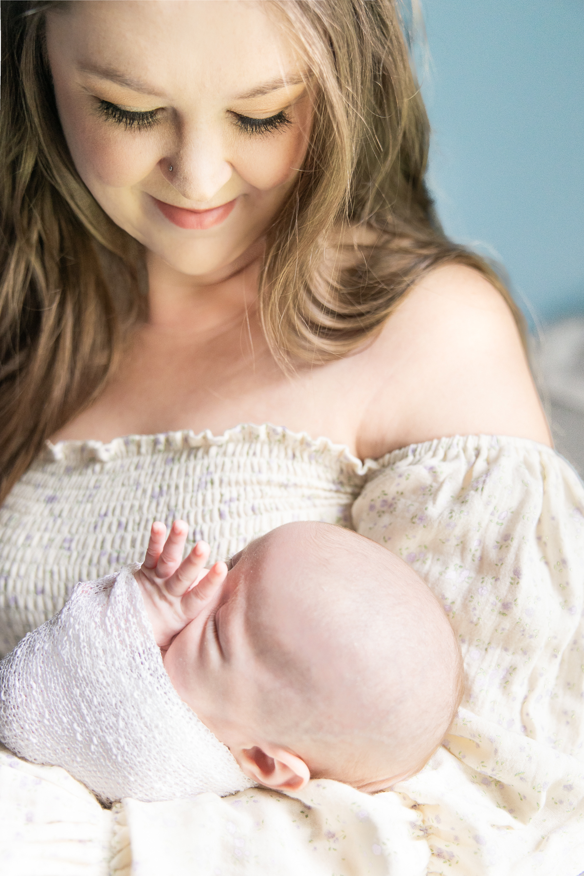 New mother looks down at the baby in her arms and smiles, Indianapolis lifestyle newborn photographer
