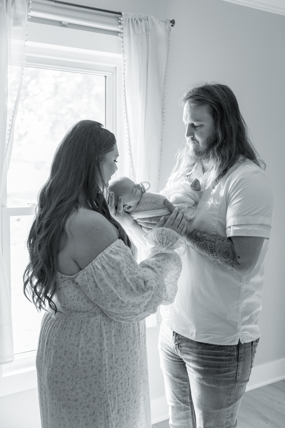 black and white image of parents holdinga newborn baby in his nursery, lifestyle newborn photography