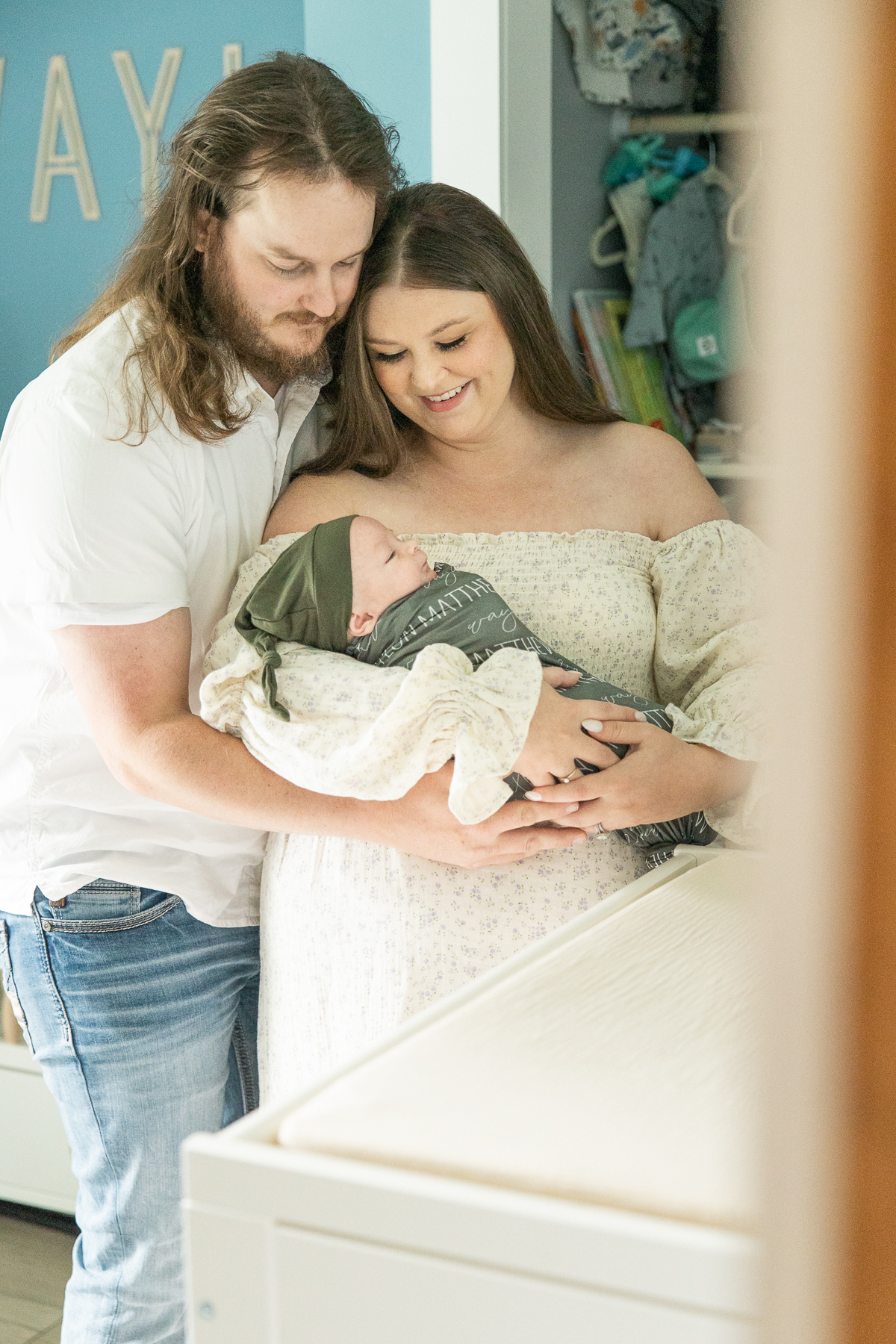parents holding and looking down at newborn baby boy by the changing table, lifestyle newborn photography