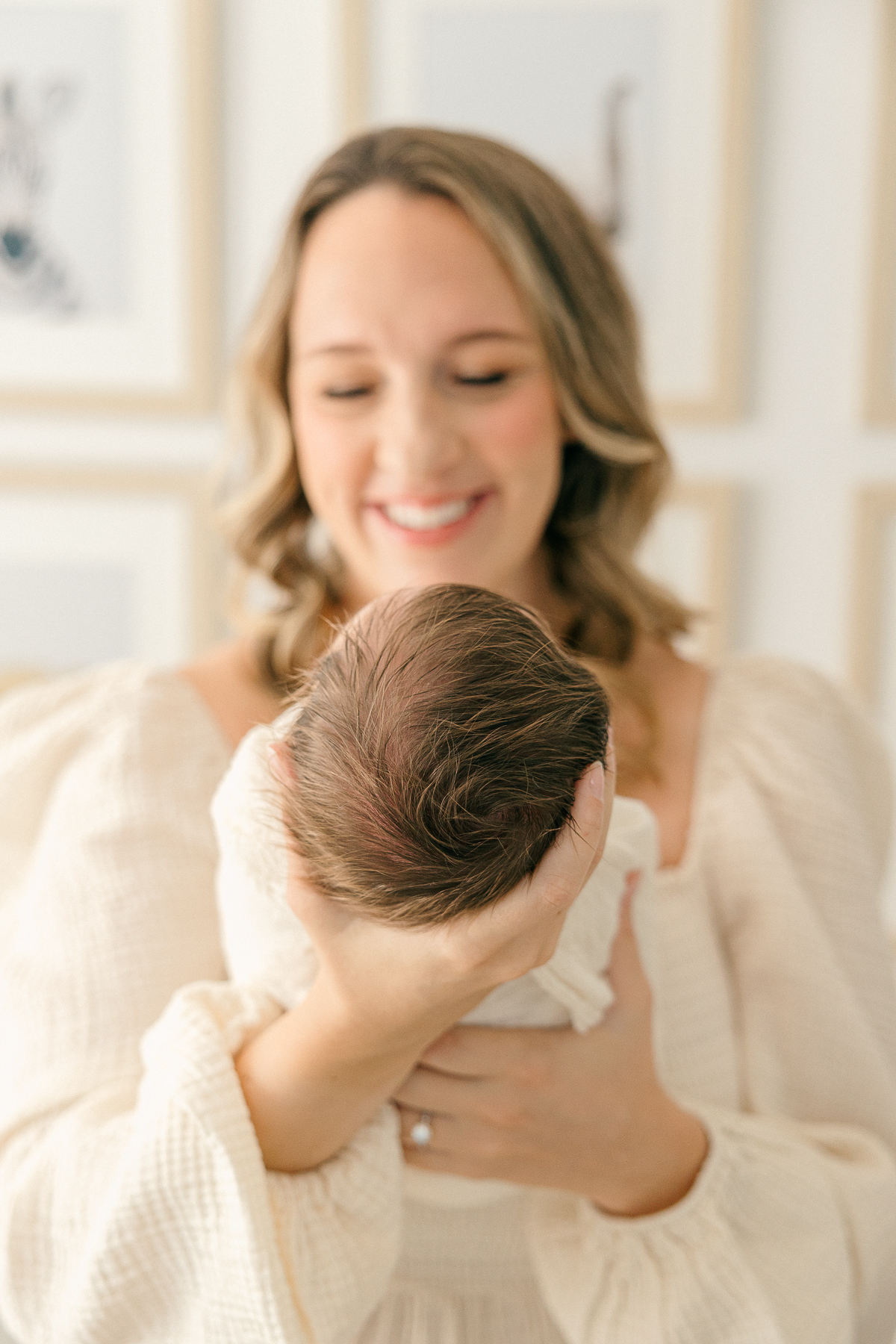 New mother holds newborn in the nursery while smiling, Indianapolis Photographer