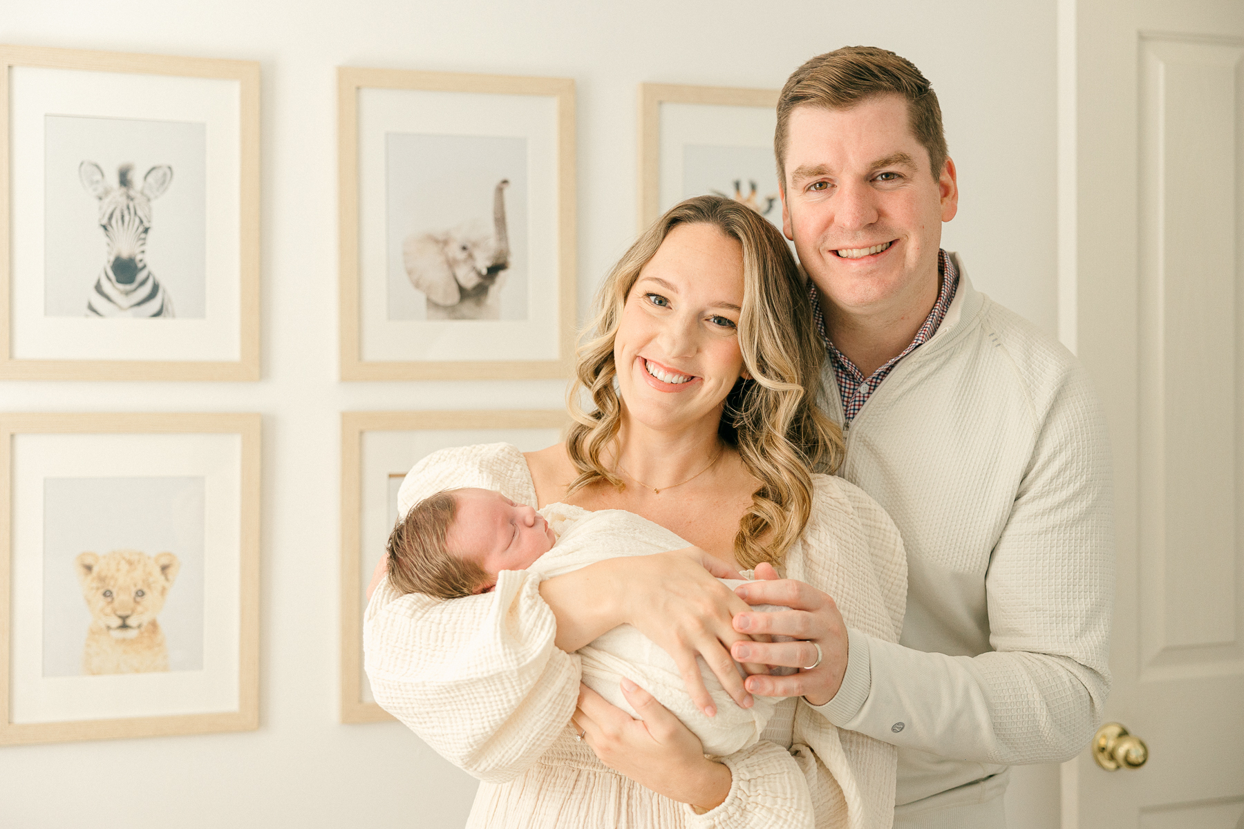 New mother and father holding their baby swaddled in cream in the nursery while smiling, Indianapolis Photographer
