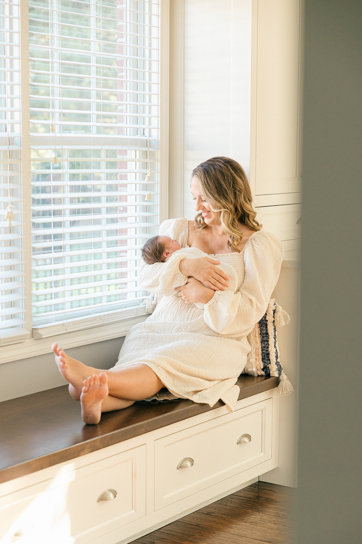 New mother holds her newborn while sitting by the window, Indianapolis Photographer