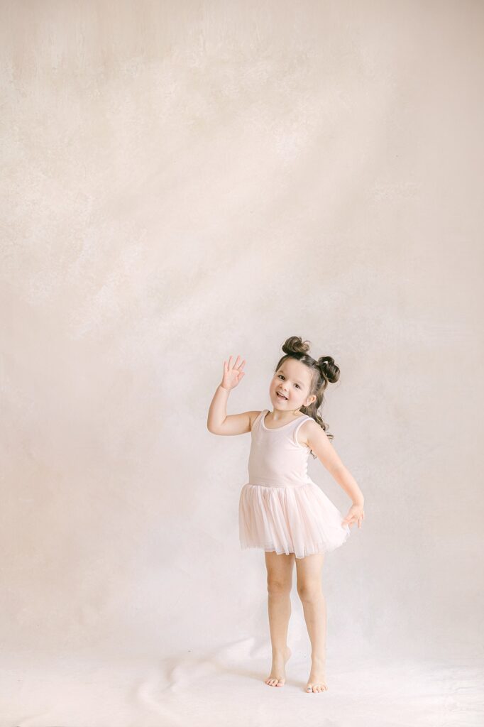 young girl in pink tutu with her hair in space buns smiles as she dances for mommy and me classes in Indianapolis