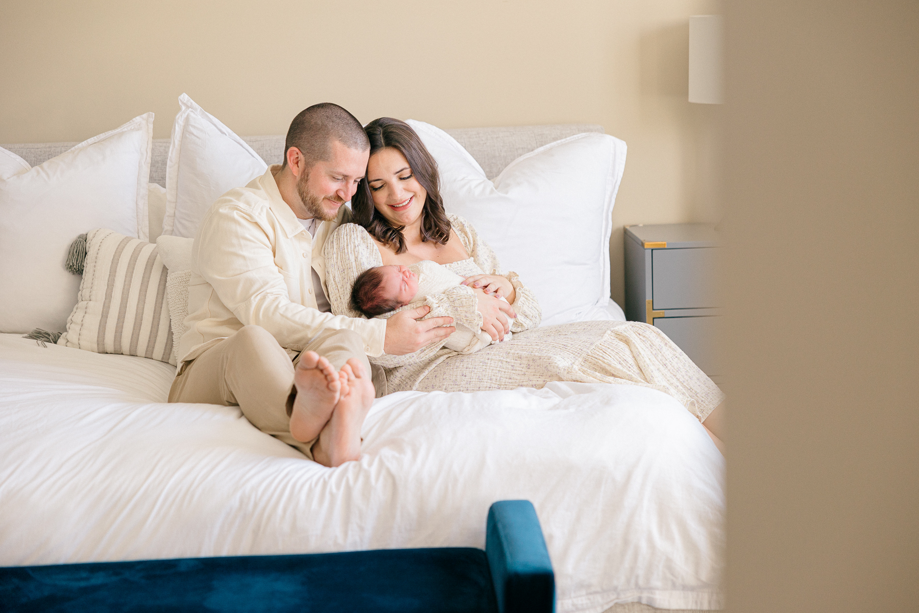 parents hold newborn baby while siting in their bed, Fishers lifestyle photography