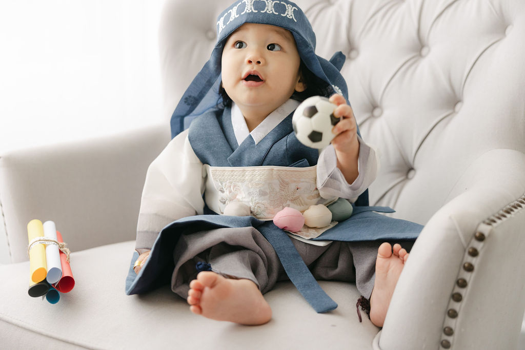 A young boy sits on a large chair playing with a mini soccer ball after meeting indianapolis babysitters