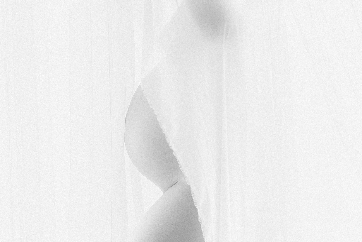 close up of mother's bare baby bump partially covered by a sheer fabric during prenatal yoga Carmel Indiana
