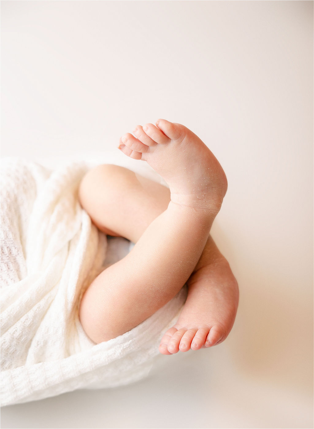 Details of a newborn baby's feet coming out of a white swaddle