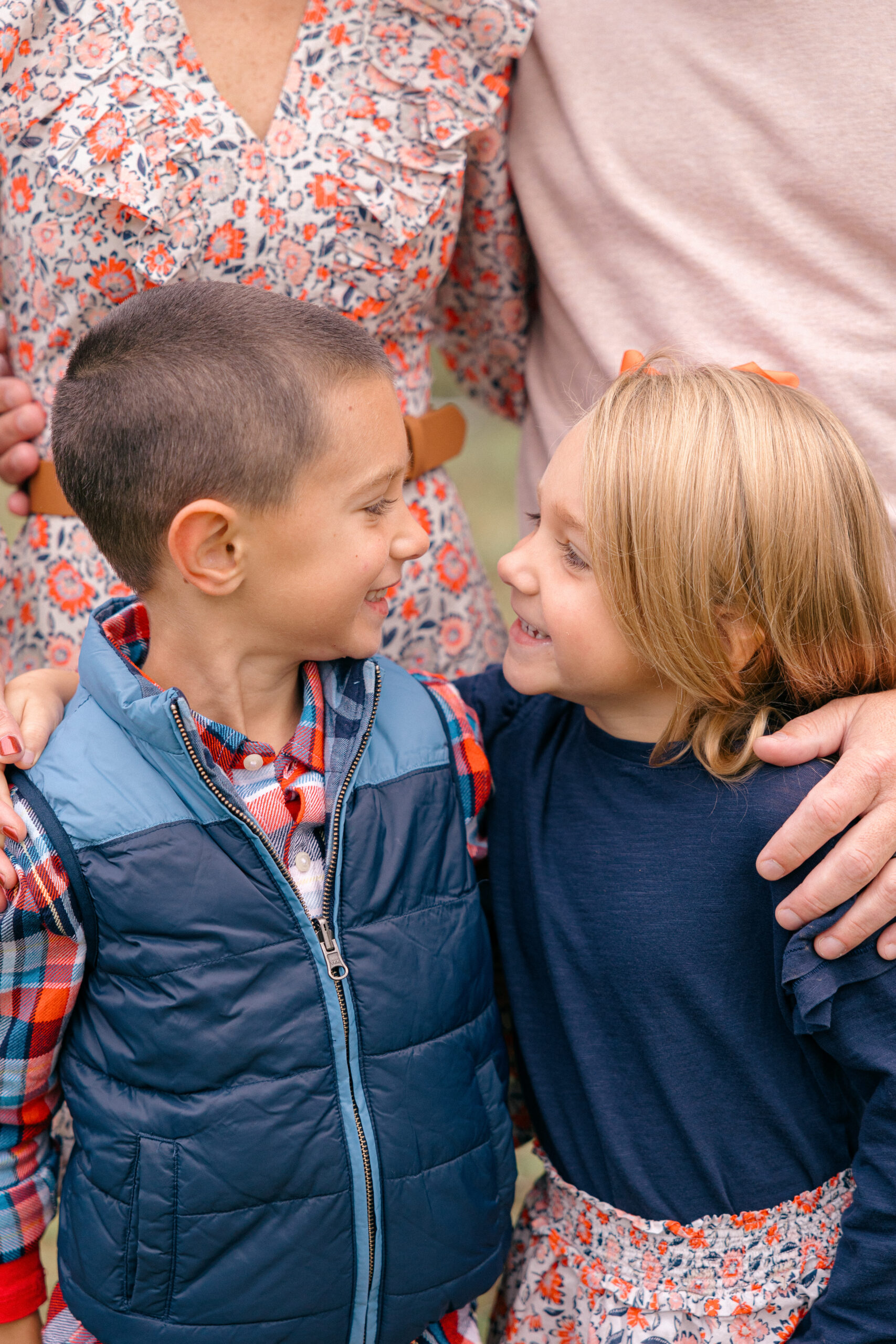 Brother and sister look at eachother while standing in front of their parents during fall family photos in Indianapolis