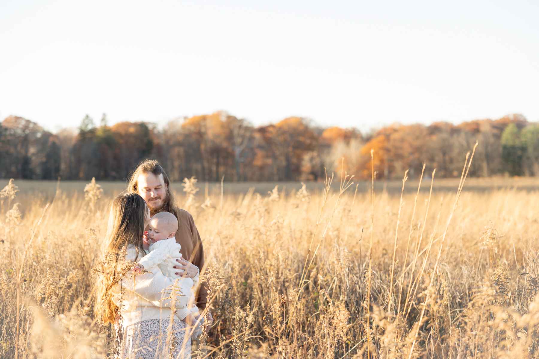 Family of 3 stands in golden field for fall family photos in Indianapolis