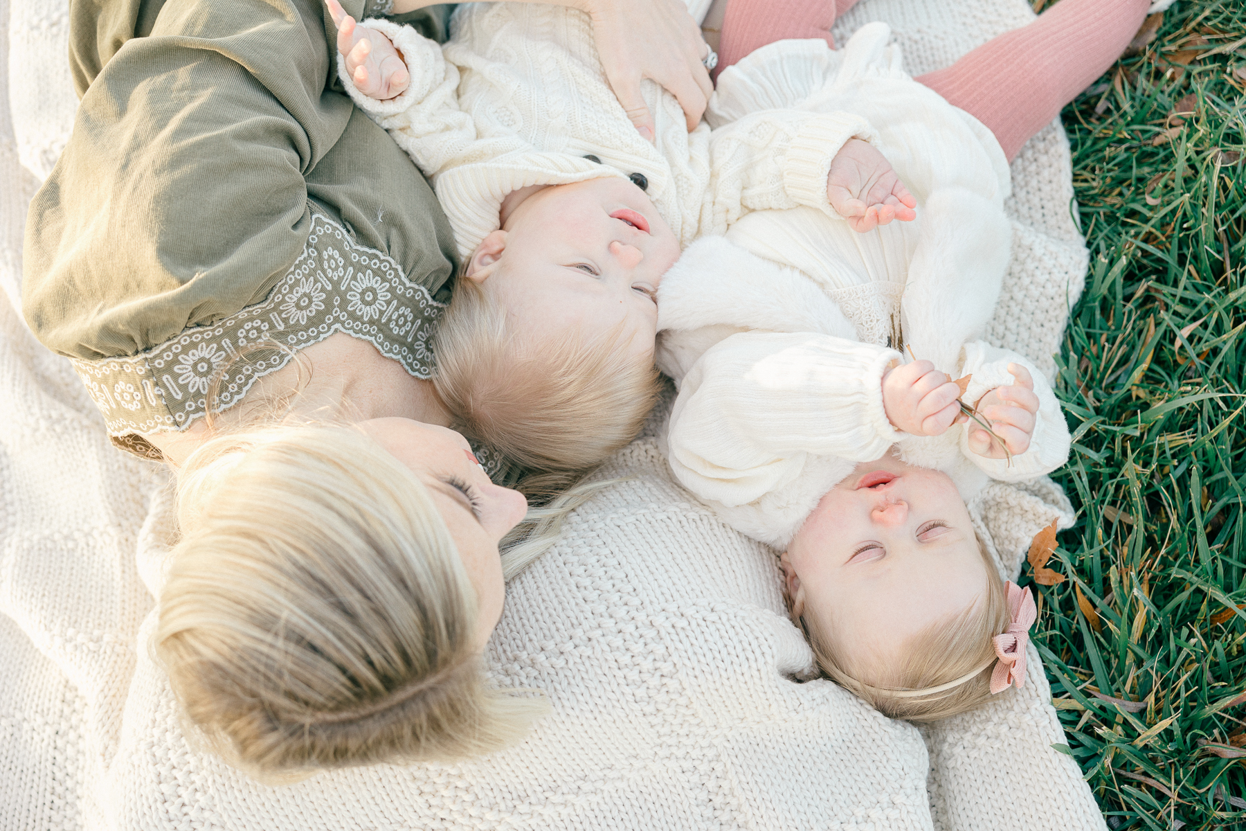 Mom and her twins lay on a cream blanket during their fall family photos in Indianapolis