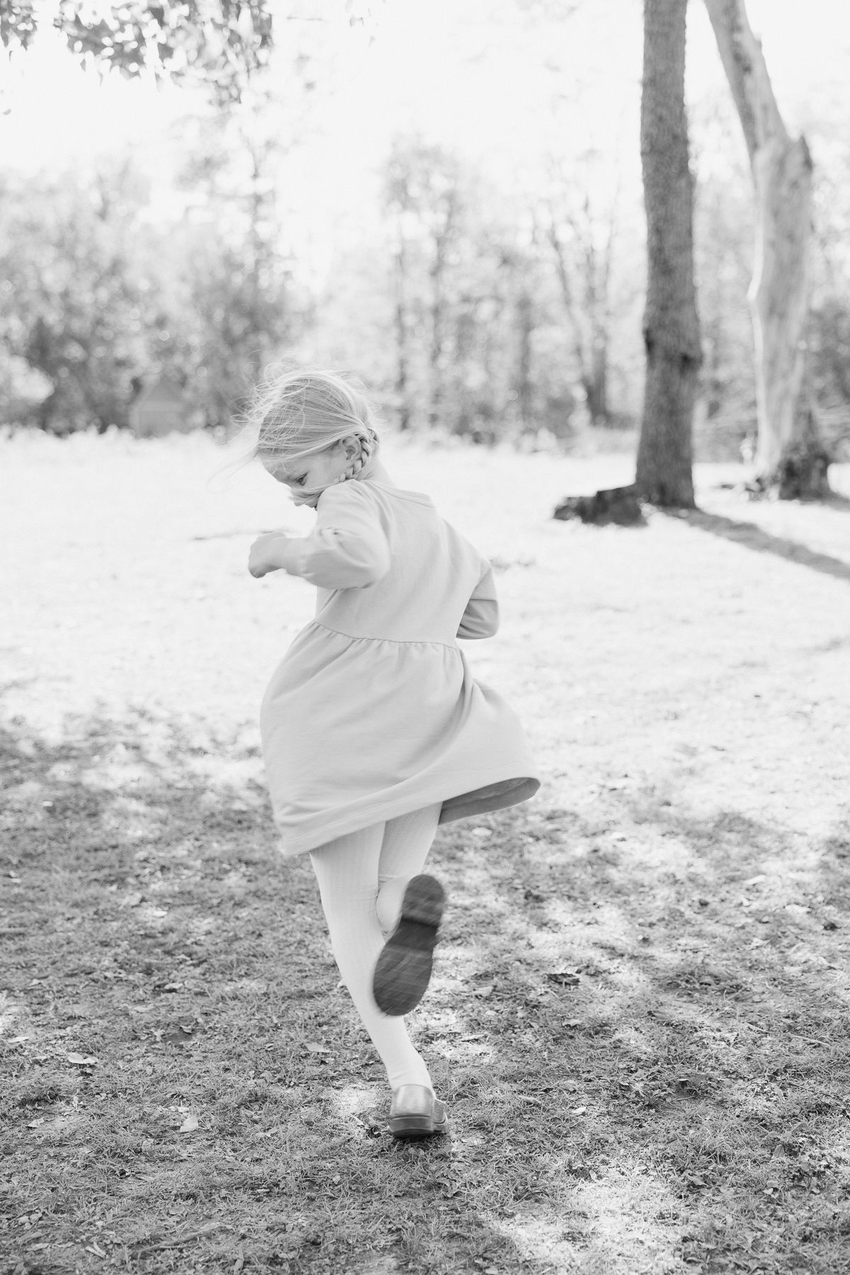 black and white image of a child twirling in her dress in an open grassy area, how to make photo sessions with kids easy