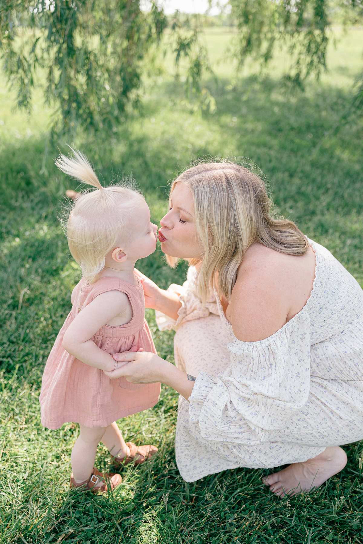 mother kisses toddler daughter under a willow true