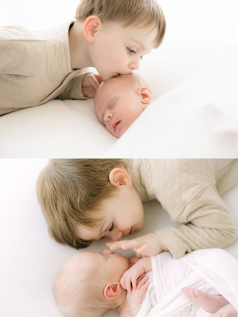3 year old boy in cream sweater lays next to his newborn brother swaddled in white and touches his nose, Zionsville Newborn picutres