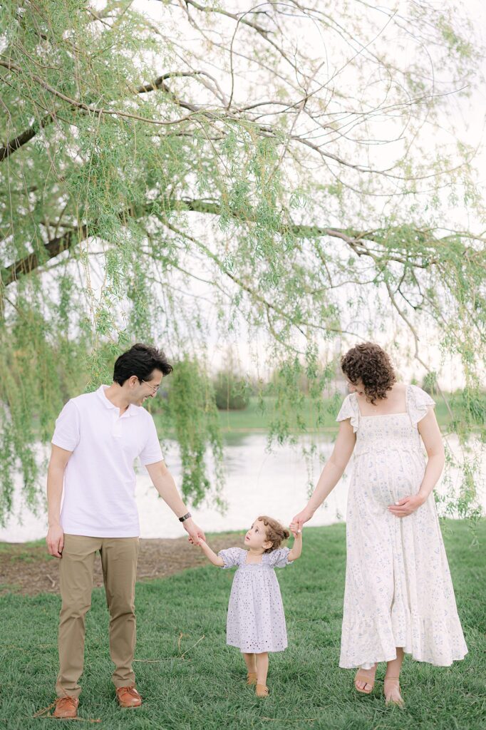 A family dressed in creams and blues shows what to wear for Indianapolis spring family photos while holding hands and walking.
