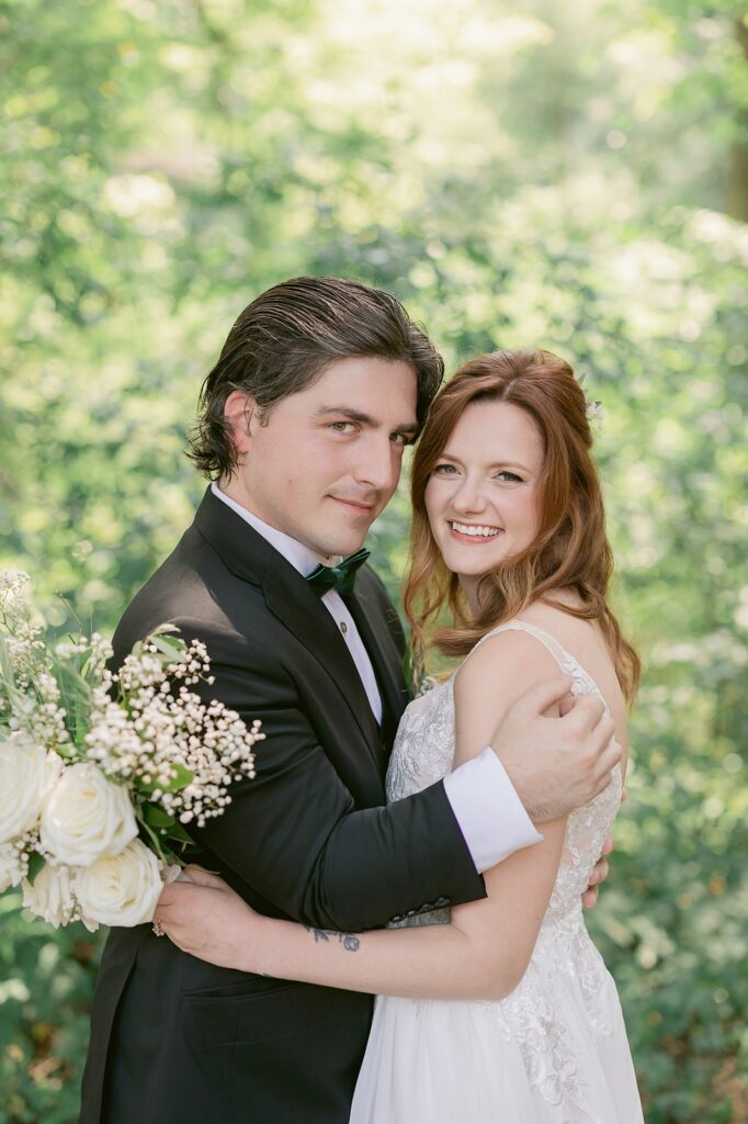 Bride and groom hugging and smiling while surrounded by lush green trees, Indiana wedding photographer 